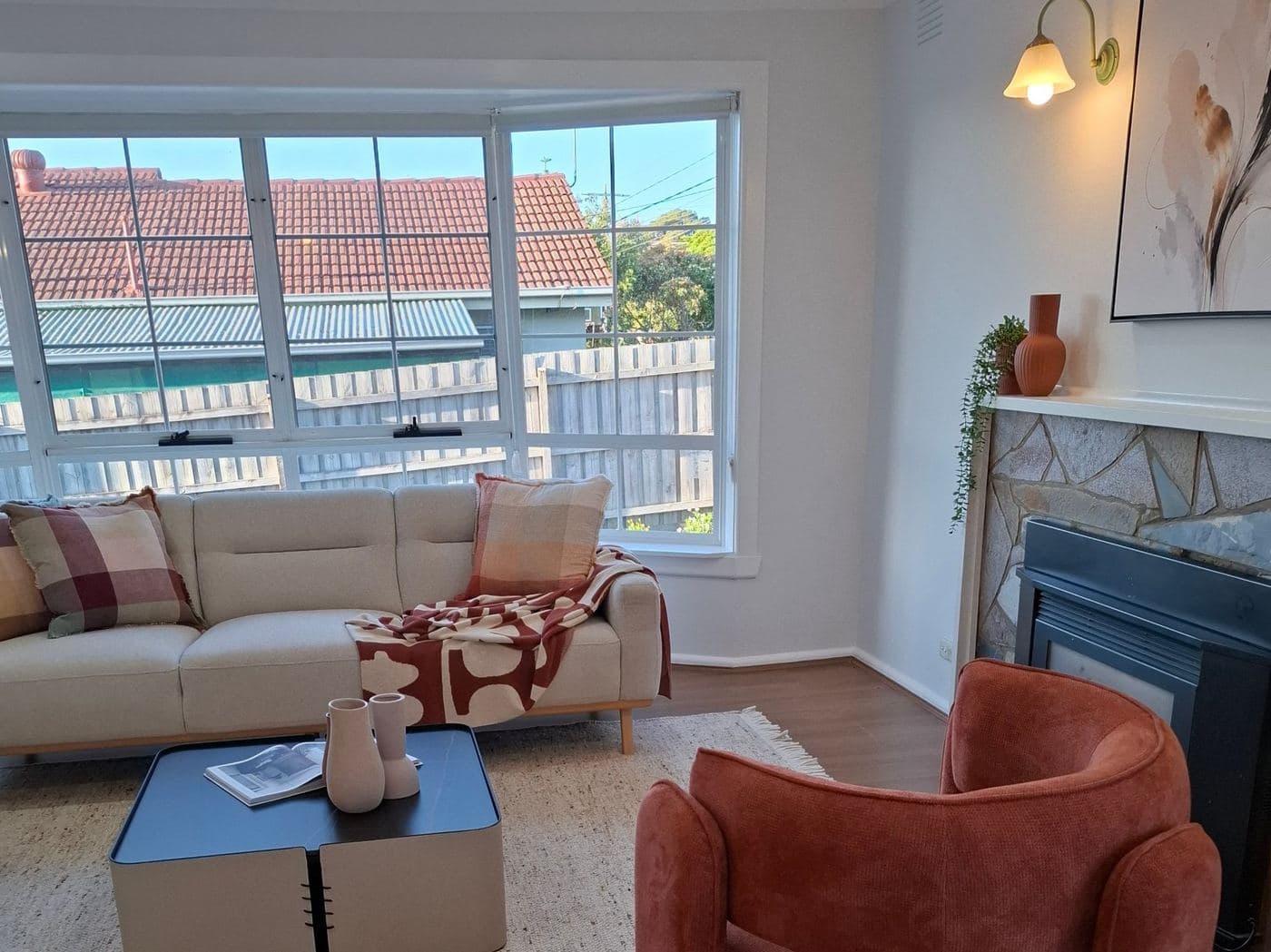 Renovated living room with a bay window, sofa and stone fireplace, styled for sale